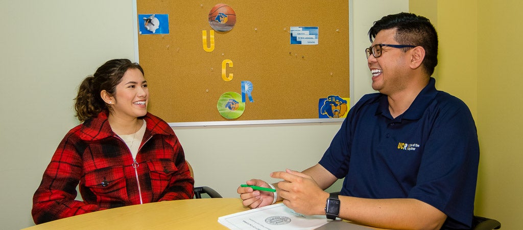 A UCR student meets with a member of the Regsitrar team in a counseling room.
